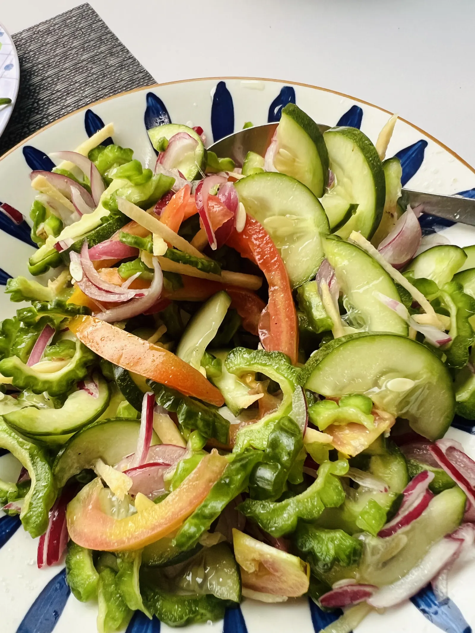 A bowl of salad with leafy greens, vegetables, egg and seeds.