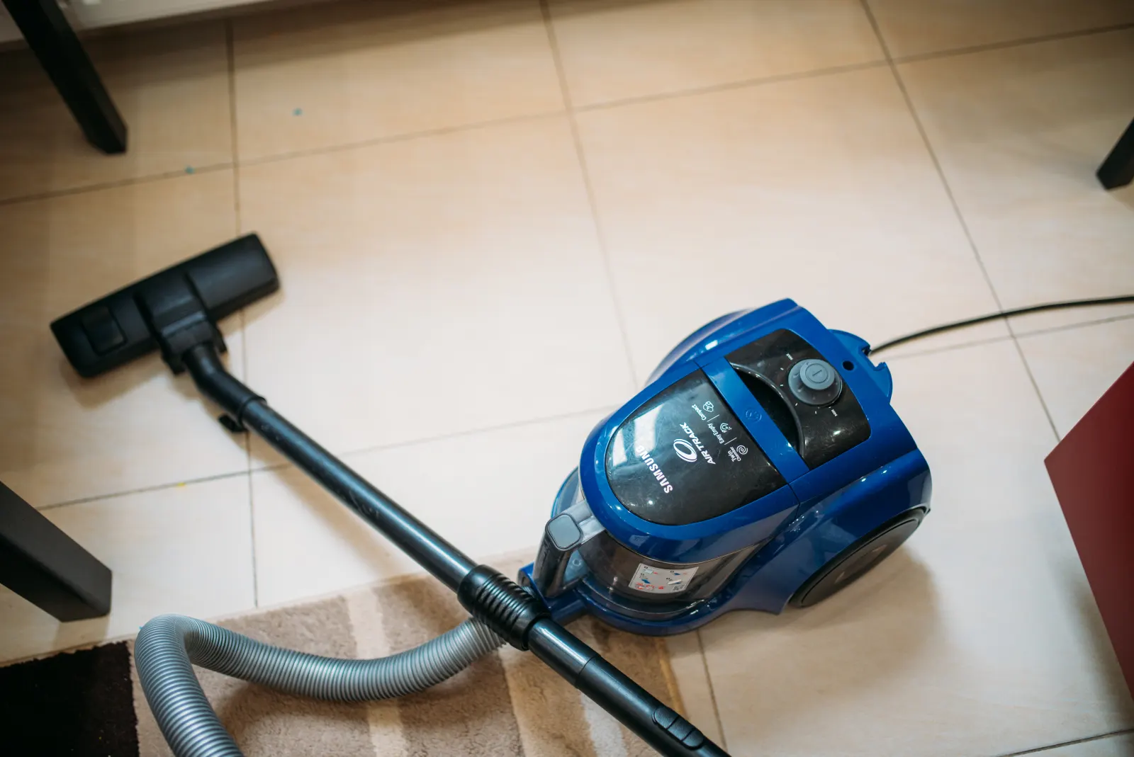 A vacuum cleaner on the floor of a bright living room.