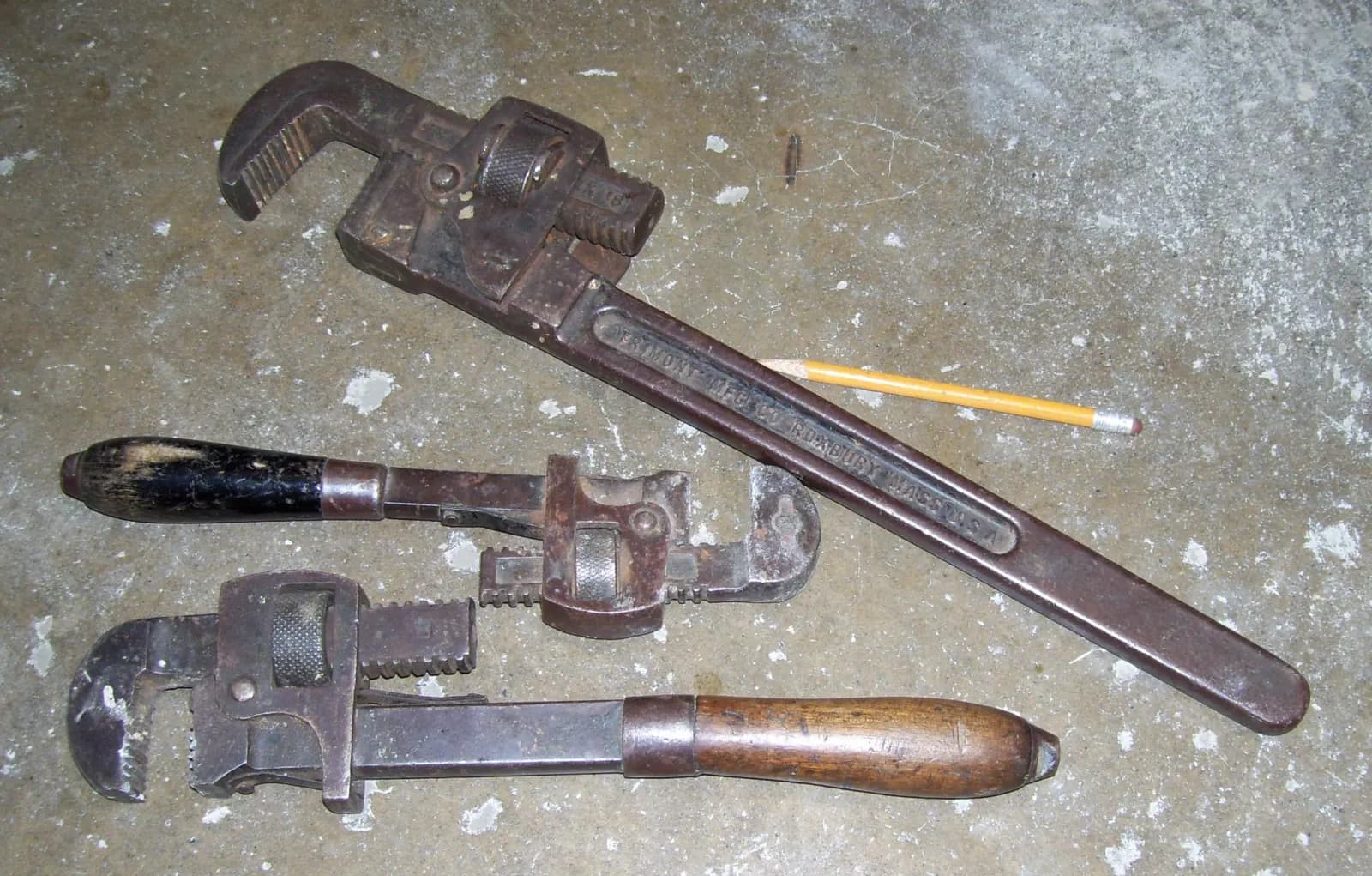 Several adjustable pipe wrenches laid side by side.