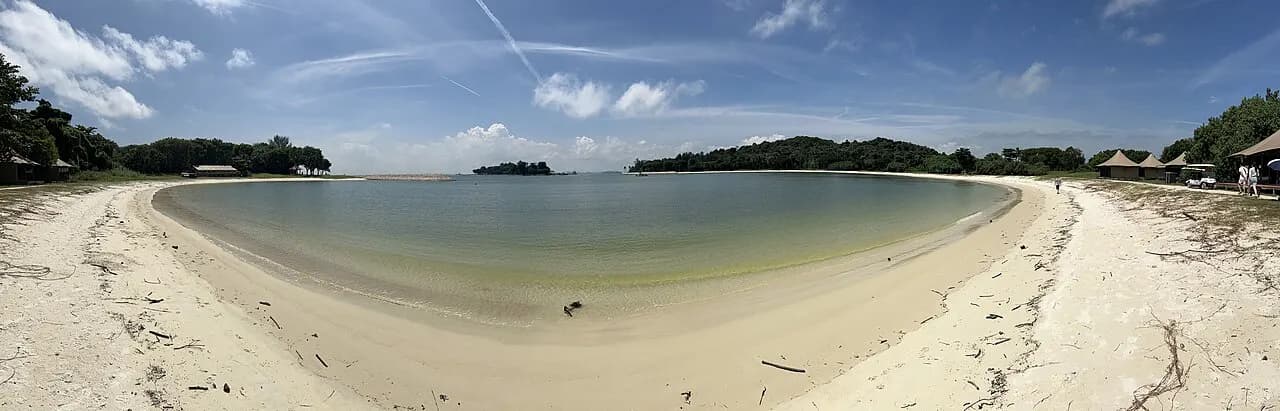 A wide view of the sand, sea and trees at Lazarus Beach in Singapore.